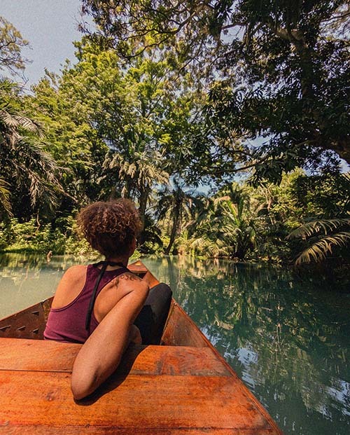 Canoe gliding across a border lake near Kilimanjaro with forest along the shoreline