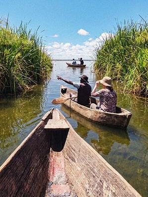 Canoe on a border lake near Kilimanjaro surrounded by lush greenery
